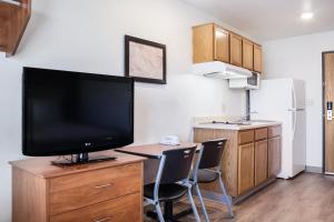 a kitchen with a tv on a dresser with two chairs at WoodSpring Suites McKinney in McKinney