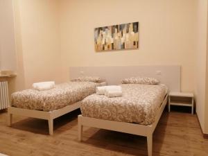 Habitación con 2 camas y una pintura en la pared. en Locanda La Francisca, en Omegna