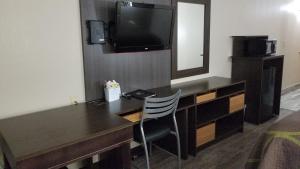 einen Schreibtisch mit einem TV und einem Stuhl in einem Zimmer in der Unterkunft Super 8 by Wyndham Dickson in Dickson