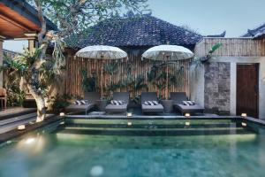 a pool with chairs and umbrellas next to a house at Sitala Suite in Ubud