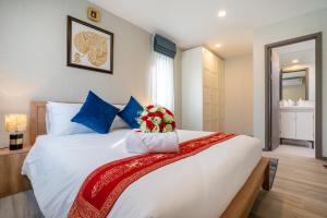 a bedroom with a large white bed with flowers on it at Luxury Apartment at Title Residencies Naiyang Beach in Phuket