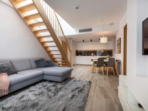 a living room with a couch and a staircase at VacationClub – Seaside Park Penthouse 608 in Kołobrzeg