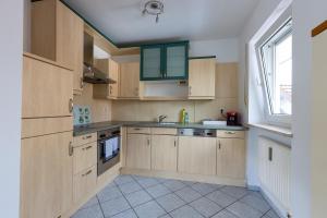 a kitchen with wooden cabinets and a window at Ferienwohnung Burgkirchen in Unterneukirchen +5 photos