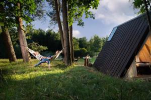 a girl swinging on a hammock next to a tree at Sandfallet Glamping in Laholm