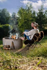 two people sitting in chairs around a fire pit at Sandfallet Glamping in Laholm