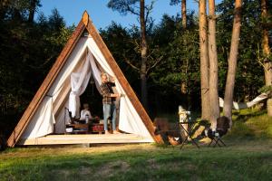 a woman standing inside of a triangular tent at Sandfallet Glamping in Laholm