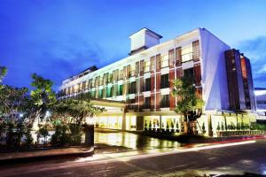 ein großes weißes Gebäude mit Bäumen davor in der Unterkunft Paradise Hotel Udonthani in Udon Thani