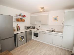 a kitchen with white cabinets and a sink and a dishwasher at Galwad Y Môr in Pwllheli