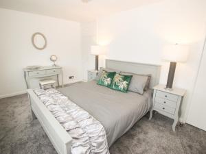 a white bedroom with a large bed with green pillows at Galwad Y Môr in Pwllheli