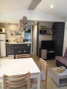cocina y sala de estar con mesa blanca y sillas en Mobil home La Mer en Vias