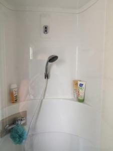 una ducha con una manguera pegada a una pared blanca en Mobil home La Mer en Vias