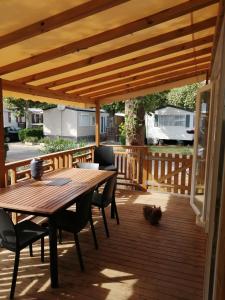 una terrazza in legno con tavolo e sedie in legno di Mobil home La Mer a Vias