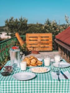 una mesa con platos de comida y vasos de leche en N'konak Guesthouse, en Pukë