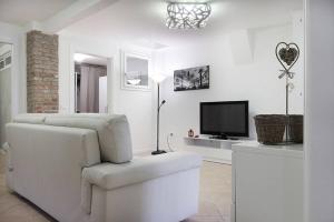 ein weißes Wohnzimmer mit einem Stuhl und einem TV in der Unterkunft Al Battello Apartments in Venedig