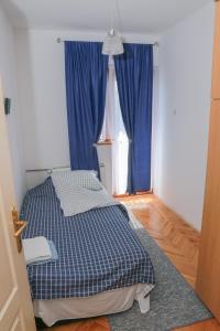 a bedroom with a bed and a window with blue curtains at Apartman Marija in Pirot