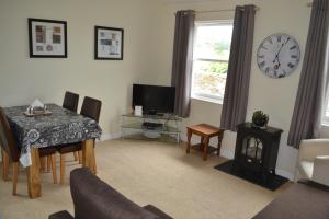 ein Wohnzimmer mit einem Tisch und einer Uhr an der Wand in der Unterkunft Dartmoor Apartments in Moretonhampstead