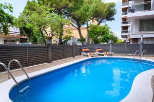 a swimming pool with two chairs and a building at 4R Casablanca Playa in Salou