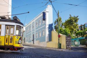 Eine gelbe Straßenbahn fährt eine Straße entlang neben einem Gebäude in der Unterkunft Saudade Micro Loft - Santos in Lissabon