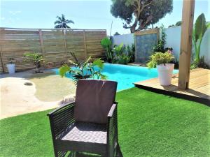 une chaise assise sur l'herbe à côté d'une piscine dans l'établissement Fleur de passion, à Saint-André