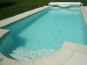 une grande piscine d'eau bleue dans l'établissement Ferme de Launay, à Chançay