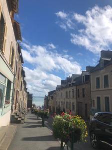 una calle de la ciudad con edificios y flores en un soleado en Appartement Rue Victor Hugo - Port de la Houle, en Cancale
