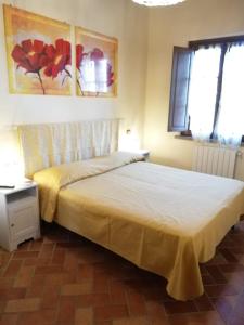 a bedroom with a bed with a yellow bedspread and two windows at L'Aia degli olivi in Vada