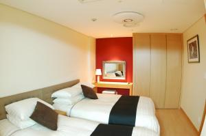 two beds in a hotel room with red walls at Keumho Jeju Resort in Seogwipo