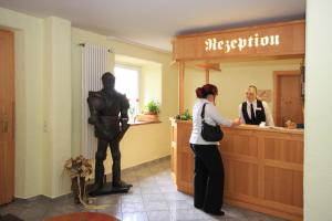 Eine Frau, die am Tresen eines Ladens mit einer Statue steht. in der Unterkunft Hotel Trasen in Waldkraiburg