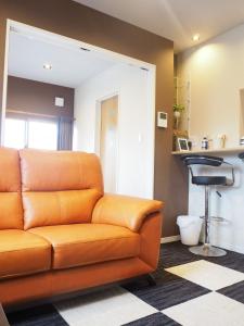an orange couch in a living room with a bar stool at Harbour Inn & Suites - Vacation STAY 8829 in Niigata