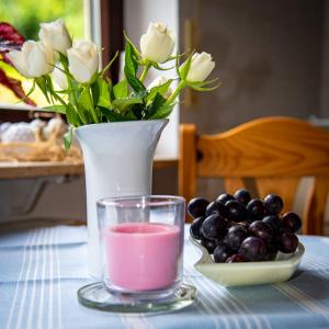 a table with a vase with a pink drink and grapes at FERIENWOHNUNG SILBERG in Dörrenbach