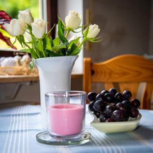 einen Tisch mit einer Vase mit einem rosa Getränk und Trauben in der Unterkunft FERIENWOHNUNG SILBERG in Dörrenbach