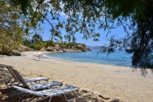 a beach with two lounge chairs and the ocean at Svolis Beachhouse - Villa Set in a Beautiful Bay in Karistos