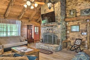 a living room with a stone fireplace and a tv at Picturesque Log Cabin Less Than 1 Mile to Table Rock Lake! in Golden