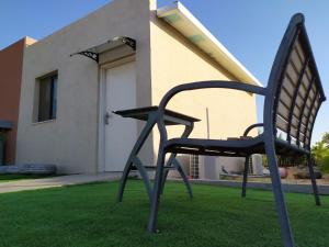 una silla negra sentada en el césped frente a una casa en the comfort place רותם המדבר, en Merhav Am