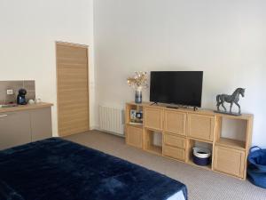 a bedroom with a television on a wooden entertainment center at Une chambre au Haras in Céreste