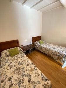 sypialnia z 2 łóżkami i drewnianą podłogą w obiekcie Le Casette nel Borgo Vicolo di Siena w mieście Pitigliano