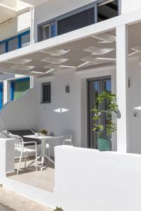 ein weißes Haus mit einem Tisch und Stühlen auf einer Terrasse in der Unterkunft Marina's Suites in Naxos Chora