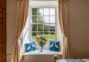a window with a vase of flowers on a window sill at Whicham Hall in Silecroft