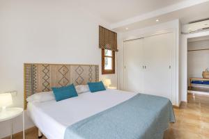 a bedroom with a large white bed with blue pillows at Villa Cala dor in Cala d´Or +35 photos