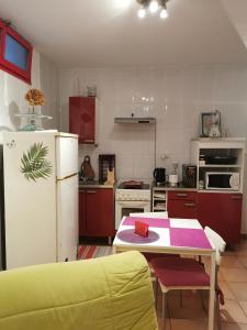 a kitchen with a table and a white refrigerator at APPARTEMENT EN SOUS SOL DE VILLA avec accès jardin et piscine in Marseille