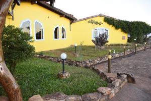 a yellow building with a yard with a stone curb at Hotel Catavento in Cristalina
