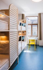 a room with bunk beds with a table and a yellow stool at NETIZEN Budapest Centre in Budapest