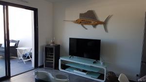 ein Wohnzimmer mit einem TV und einem Fisch an der Wand in der Unterkunft Appartement neuf T2 centre de Porticcio in Porticcio
