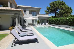 a villa with a swimming pool and lounge chairs at Charming Exceptional Golf Villa in Algarve in Faro