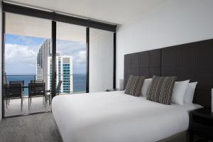 una camera da letto con un grande letto bianco e una grande finestra di Mantra Circle On Cavill a Gold Coast Altre 37 foto