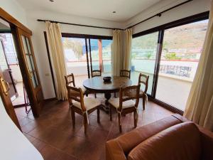 a dining room with a table and chairs and a couch at luxury penthouse with ocean and beach views in Puerto de Mogan in Puerto de Mogán