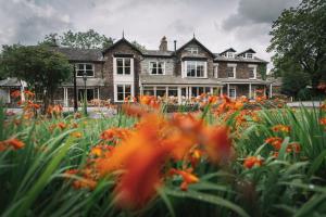 a house with a field of flowers in front of it at Bridge House Hotel & Silver Howe View Cottage in Grasmere