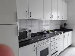 歐勒洛斯聖克魯斯的住宿－Duplex santa cruz，厨房配有白色橱柜、水槽和微波炉