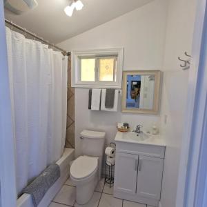 Baño blanco con aseo y lavamanos en Knotty Pine Ocean Front Cabin - Adults Only, en Ingonish