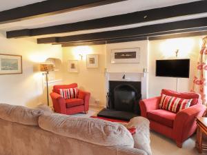 a living room with two red chairs and a fireplace at Milkwood Cottage in Fishguard +6 photos
